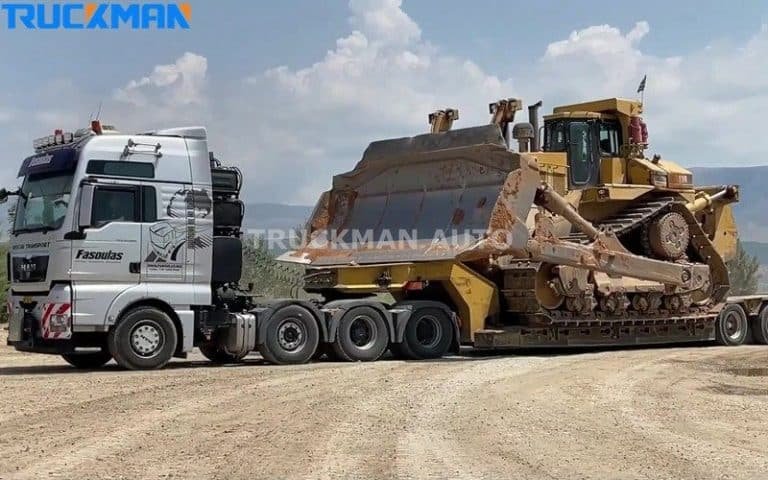 Heavy-duty low-chassis semi-trailer truck hauling a large yellow bulldozer, demonstrating the trailer's high load capacity and rugged design