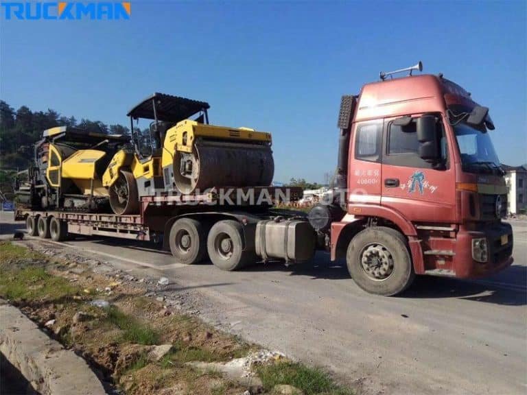 Low bed semi-trailer loaded with yellow construction rollers, adaptability to all types of construction equipment.
