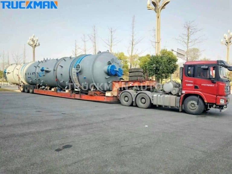Semirremolque rojo de plataforma baja que transporta equipos industriales sobredimensionados: transporte versátil de mercancías pesadas