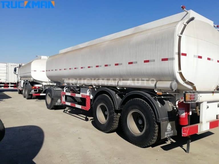 Vista traseira de um reboque de transporte de produtos químicos prateado com válvulas de segurança, afiliado à Truckman Auto