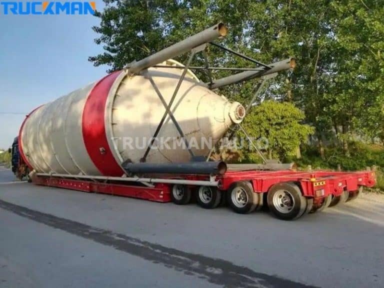 Plataforma de carga roja remolque de plataforma baja moviendo grandes componentes industriales rojos y blancos - transporte de carga extrema
