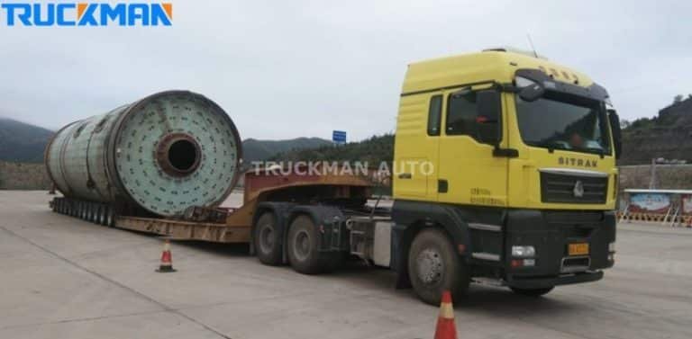 Camión Sitrak con remolque de plataforma baja en muelle de carga, equipado para el transporte de grandes bombonas de gas industrial