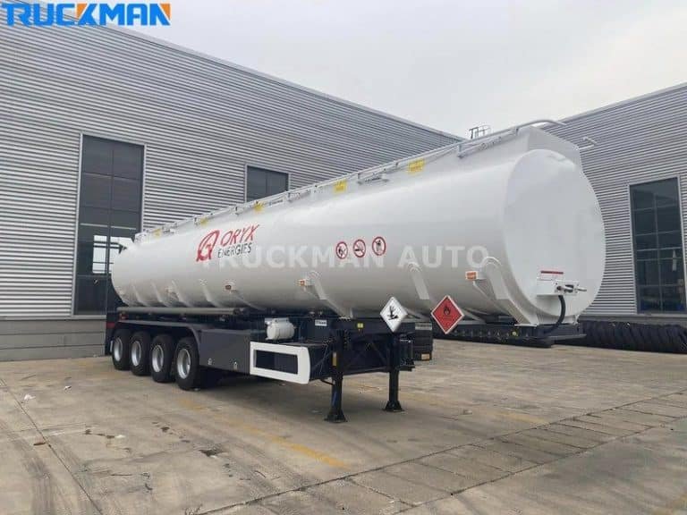 White tank trailer marked with hazardous materials sign outside warehouse