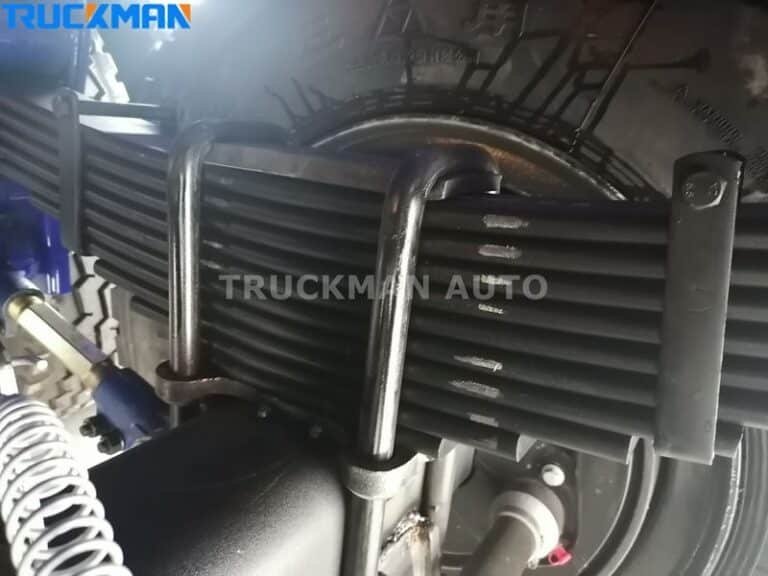 Close-up of leaf spring suspension on a flatbed semi-trailer by TRUCKMAN AUTO.