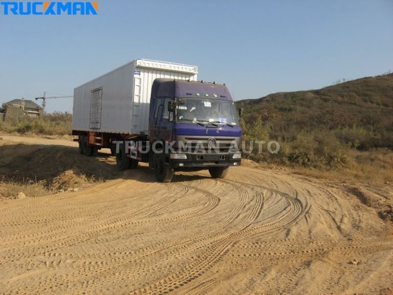Truck with a van trailer driving on a dirt road, transporting household appliances and construction materials-Truckman Automobile