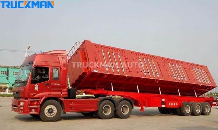 The red rear dump semi-trailer in the raised dump position with its hydraulic system in operation.
